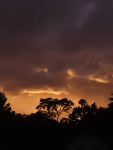 Nuvens escuras se abrem para a luz alaranjada no horizonte.