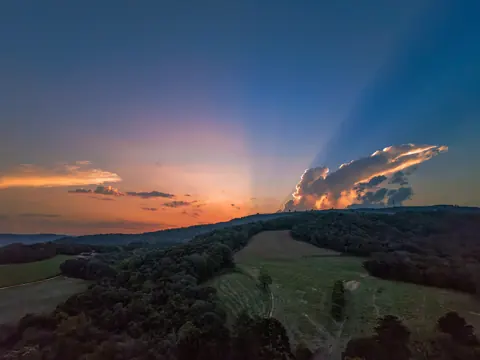 Vista aérea dos campos, das árvores e das cores do fim da tarde.